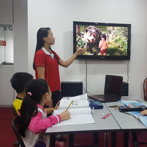 Teacher using multimedia on TV to teach kids in class