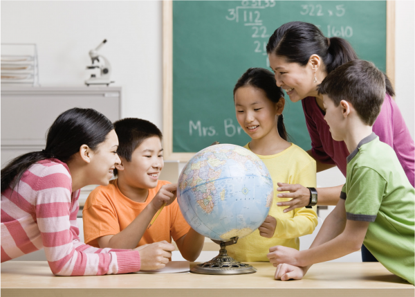 Students and teacher studying a globe of the world