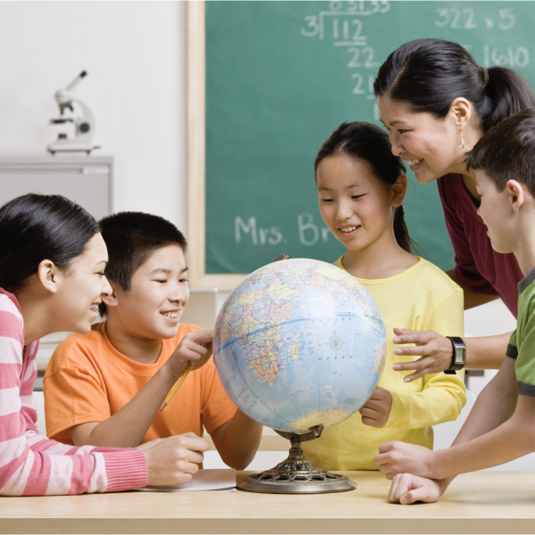 Students and teacher studying a globe of the world